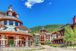 A lodge with a stone facade, multiple balconies, and a clock tower. - Lovely mountain-view condo with shared hot tub, pool & more - walk to lifts (Solitude)