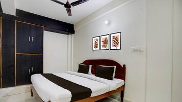 A bedroom with a bed, a wardrobe, and three framed pictures on the wall.
