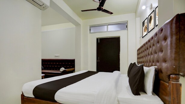 A bedroom with a wooden bed, a ceiling fan, a door, and framed artwork on the wall.