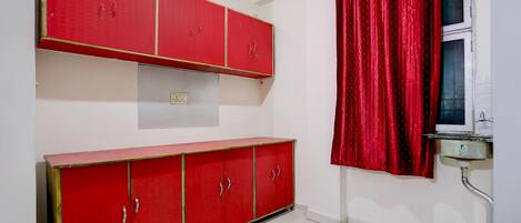 A room with a red cabinet, a red curtain, and a white sink.