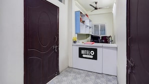 A hotel reception area with a closed door, a reception desk labeled 'HOTELO,' a ceiling fan, and a tiled floor.