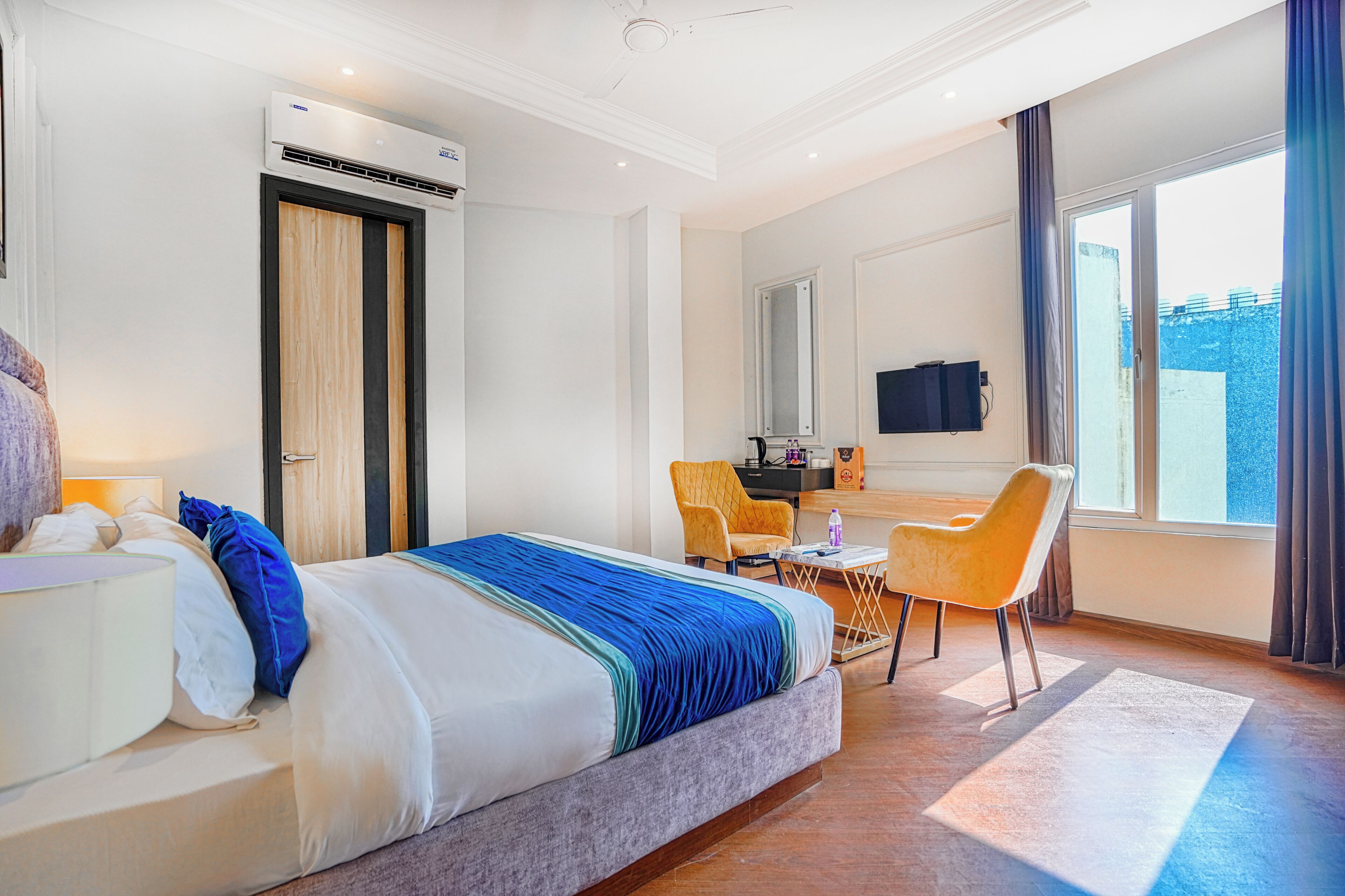 A hotel room with a bed, a desk, a chair, a TV, and a window.
