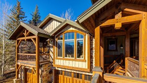 A wooden cabin with a stone foundation, a balcony, and a staircase leading to an upper level. - Luxury lodge with hot tub, sauna, game room, movie room & Deer Valley views (Park City)