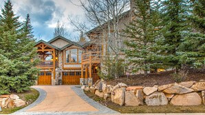 A lodge with a stone facade, wooden balconies, and a stone pathway leading to the entrance. - Luxury lodge with hot tub, sauna, game room, movie room & Deer Valley views (Park City)