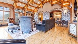 A spacious living room with a high wooden ceiling, stone archway, and a fireplace. - Luxury lodge with hot tub, sauna, game room, movie room & Deer Valley views (Park City)