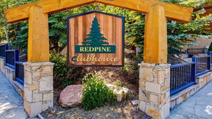 Une arche en bois surmontée d’une enseigne indiquant « REDPINE Clubhouse », le tout entouré de piliers et d’un mur en pierre.