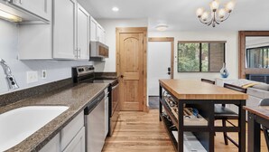 Une cuisine moderne avec des comptoirs en granit, des armoires blanches et une porte en bois.