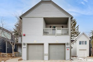 A two-story residential building with a balcony, two garages, and a small porch. - Mountain view home with hot tub, fireplace & perfect walk-to-lift location (Park City)