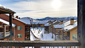 Un resort en la montaña cubierto de nieve, con edificios de varios pisos, balcones y una vista despejada de las montañas.