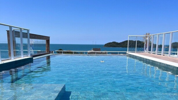 A clear blue infinity pool with a view of the sea and a small island. - Vila do Centro (Bombinhas)