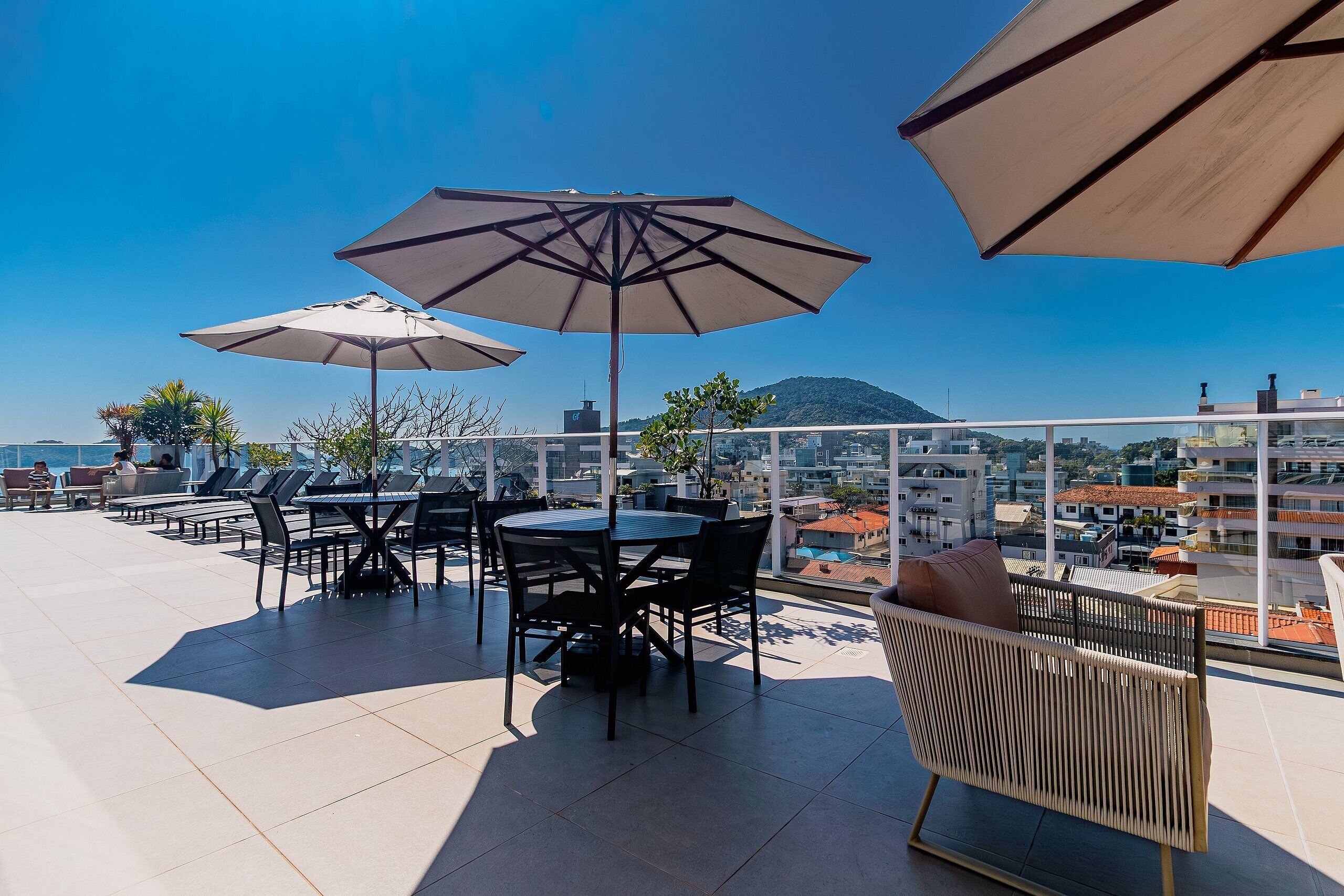 Una terraza en la azotea con mesas al aire libre, sombrillas y vistas a la ciudad.