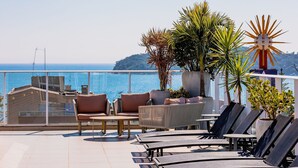 A terrace with lounge chairs, a table, and potted plants. - Vila do Centro (Bombinhas)