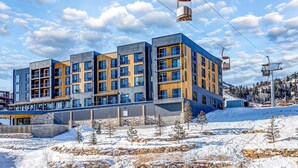 A modern multi-story building with a ski lift, surrounded by snow and trees. - Walk-to-lift studio with hot tub, sauna, pool, gym, & game room - Dog friendly (Park City)