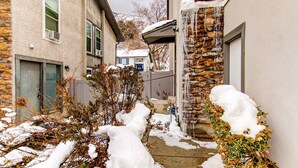 En bostadsbyggnad med en fasad av sten, en väl synlig dörr och en snötäckt mark.