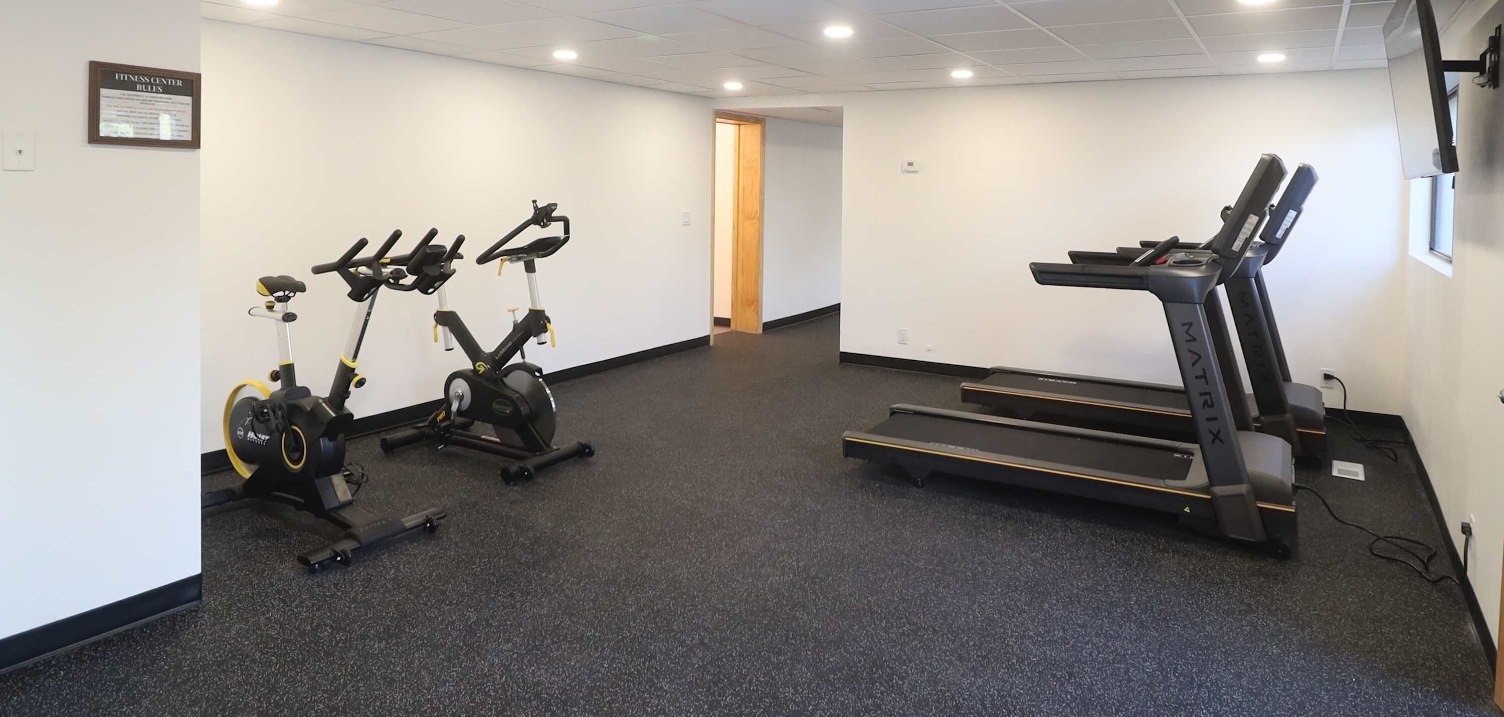 A fitness center with stationary bikes, a treadmill, and a wall-mounted mirror.