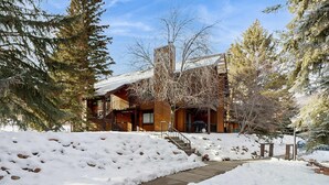 Un edificio in legno con il terreno imbiancato dalla neve e un sentiero in pietra che conduce all'ingresso.