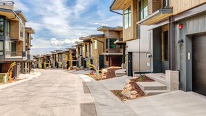 Una calle residencial moderna con fachadas de madera, cielo despejado e hidrante.