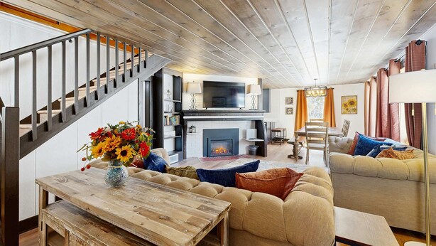 Ein gemütliches Wohnzimmer mit Kamin, einer Couch, einem Couchtisch und einer Treppe.