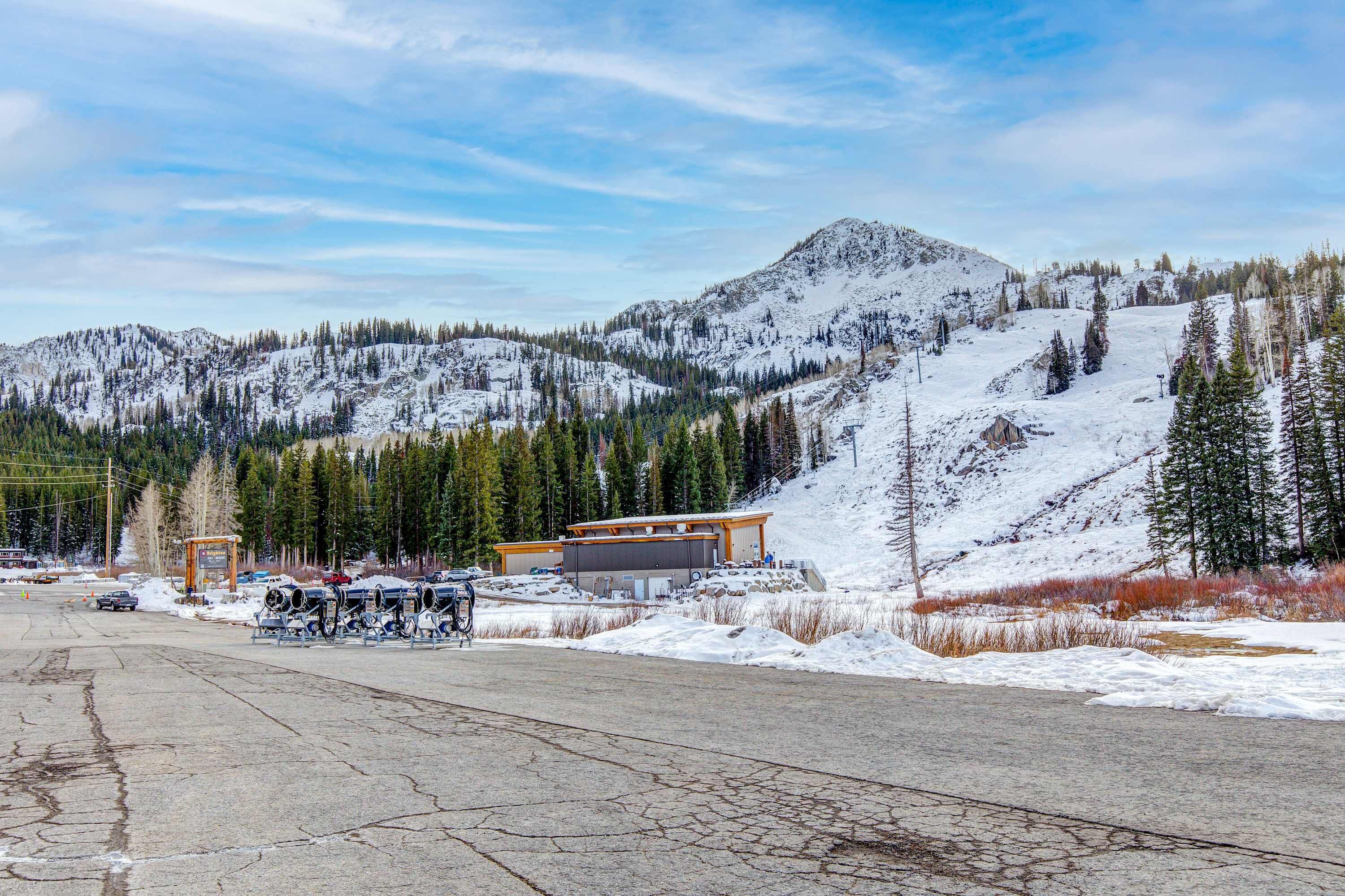 A snow-covered mountainous landscape with a building and parked vehicles.