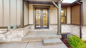 A house entrance with a stone foundation, a covered porch, and a double door. - Bright Spacious & Modern Condo with fireplace and gas grill (Heber City)
