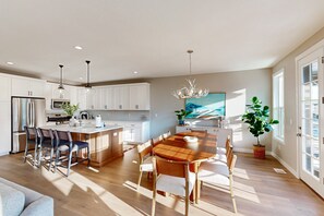 Una cocina moderna con armarios blancos, una mesa de comedor de madera y taburetes de bar.