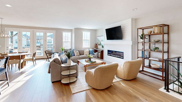 A spacious living room with a fireplace, a television mounted on the wall, and a dining area with natural light. - Bright Spacious & Modern Condo with fireplace and gas grill (Heber City)