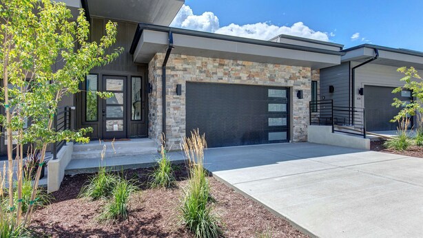 A modern two-story house with a stone facade, a garage, and a landscaped front yard. - Townhouse in Hideout with hot tub (Hideout)