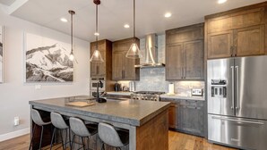 A modern kitchen with a central island, bar stools, stainless steel appliances, and wooden cabinets. - Townhouse in Hideout with hot tub (Hideout)