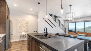A modern kitchen with a large island, stainless steel appliances, pendant lighting, and a view of the outdoors. - Townhouse in Hideout with hot tub (Hideout)