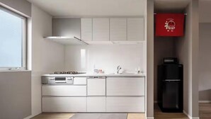 Una cocina moderna con armarios blancos, un refrigerador negro y un letrero rojo en la pared.