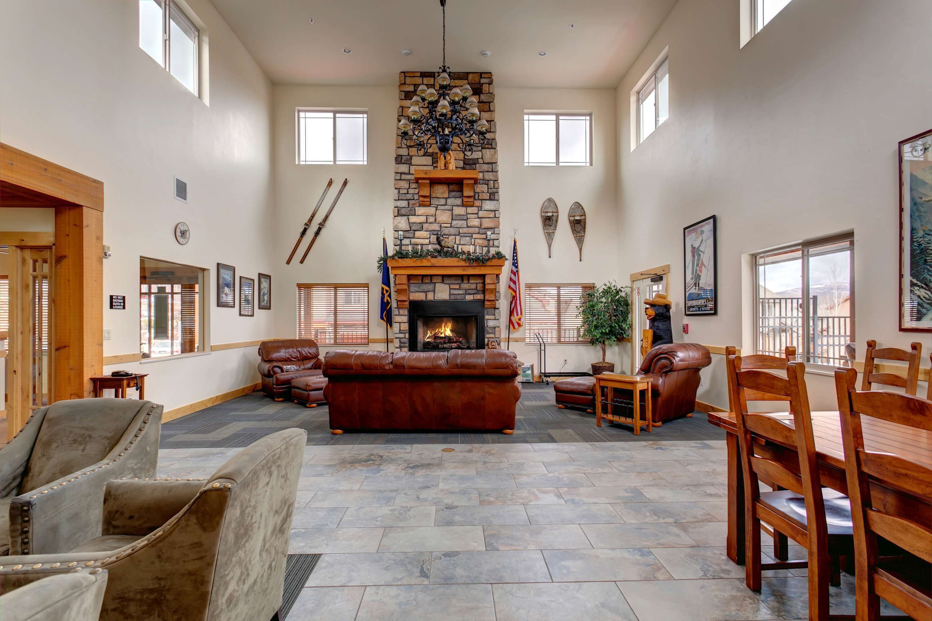 A spacious living room with a stone fireplace, leather furniture, and a view of the outdoors.