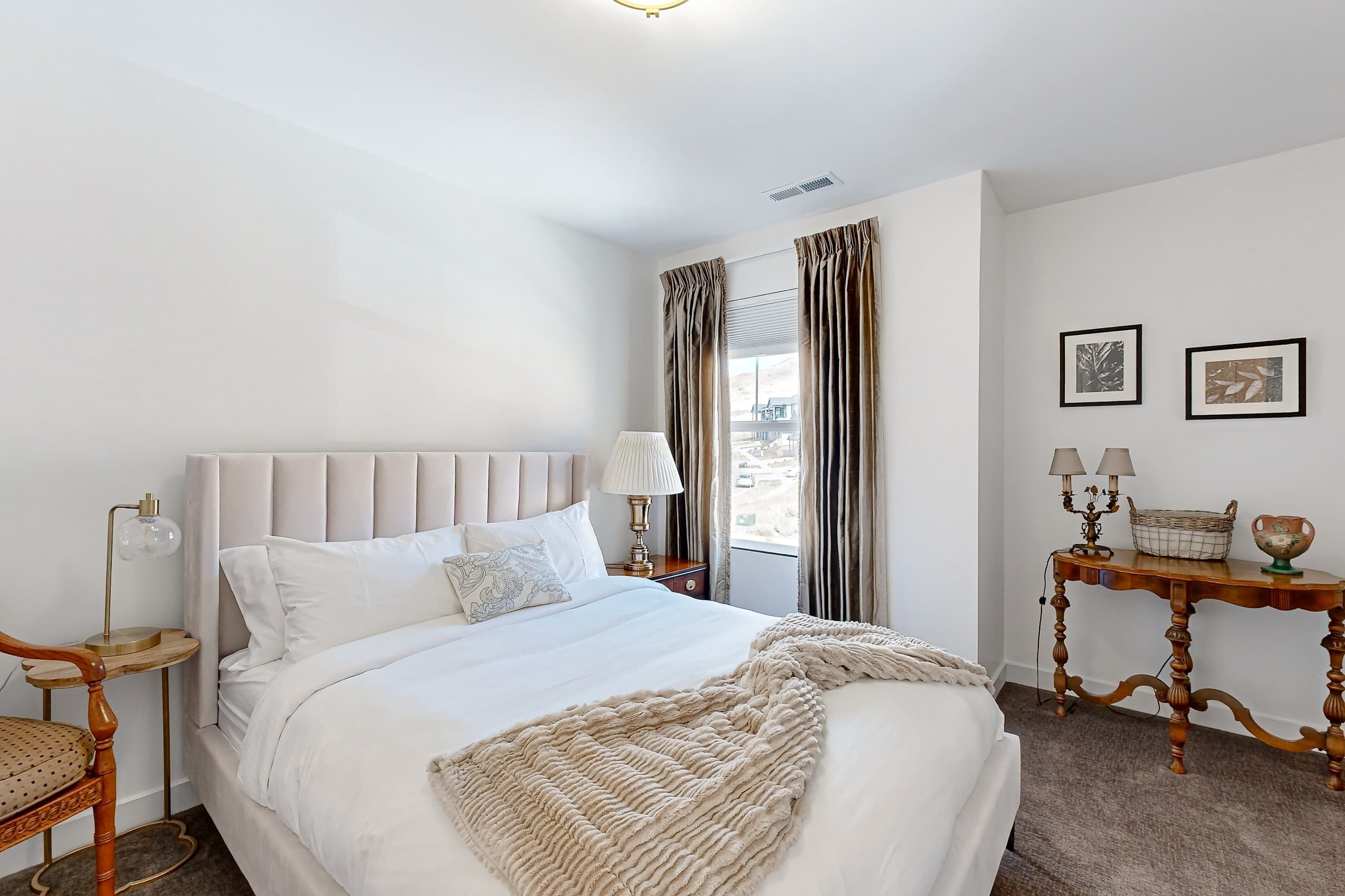 Een keurig opgemaakt slaapkamer met een bed, nachtkastje, lamp en uitzicht.