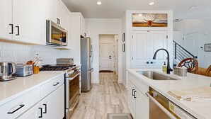 A modern kitchen with white cabinets, stainless steel appliances, and a wooden floor. - Stunning townhome with  unobstructed views, amenities for the health conscious (Heber City)