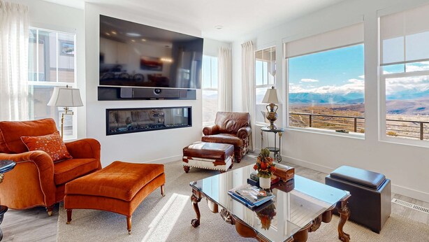 A spacious living room with a large TV, leather furniture, a glass coffee table, and a view of the mountains. - Stunning townhome with  unobstructed views, amenities for the health conscious (Heber City)