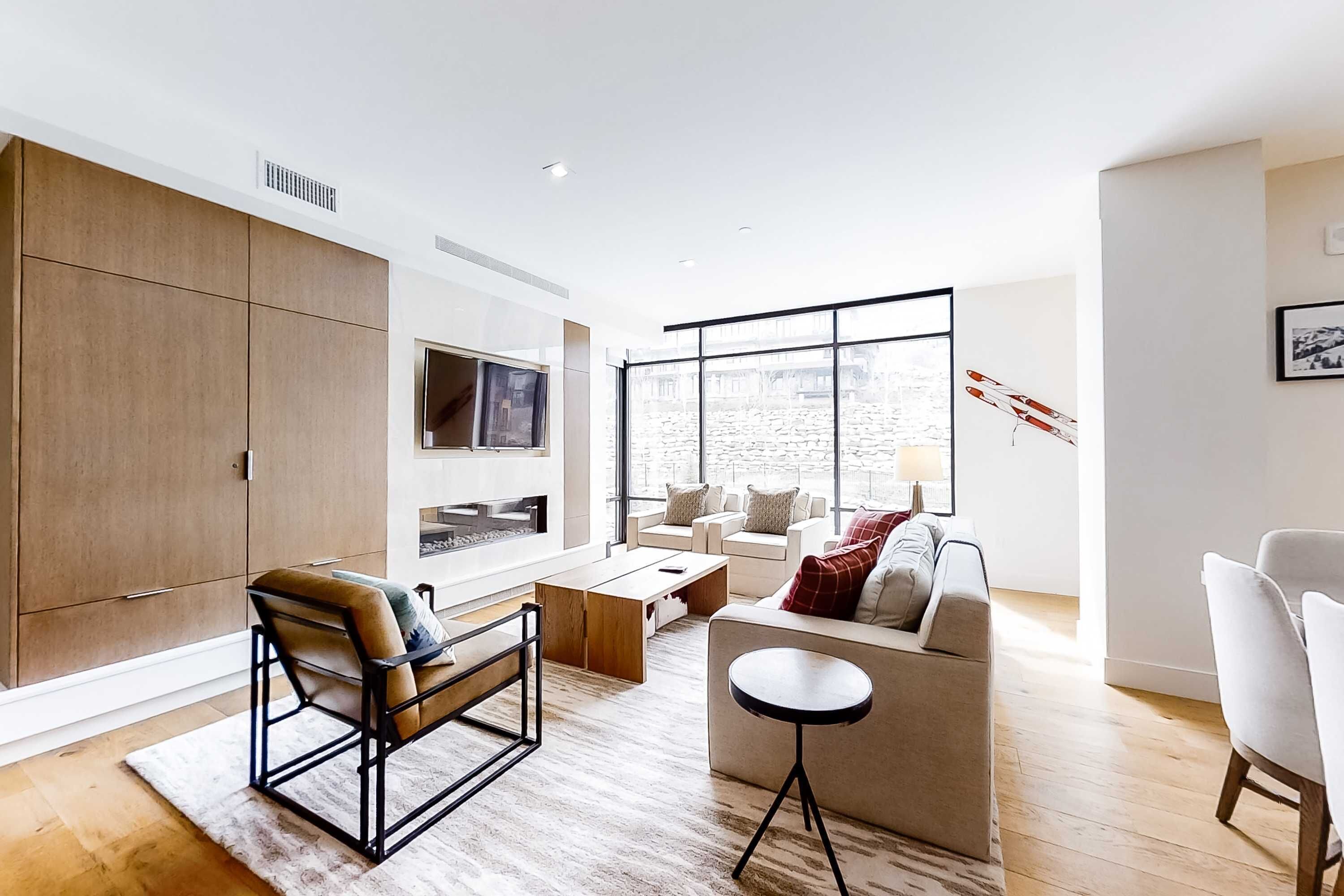 Ein modernes Wohnzimmer mit Sofa, Sessel, Couchtisch und Fernseher.
