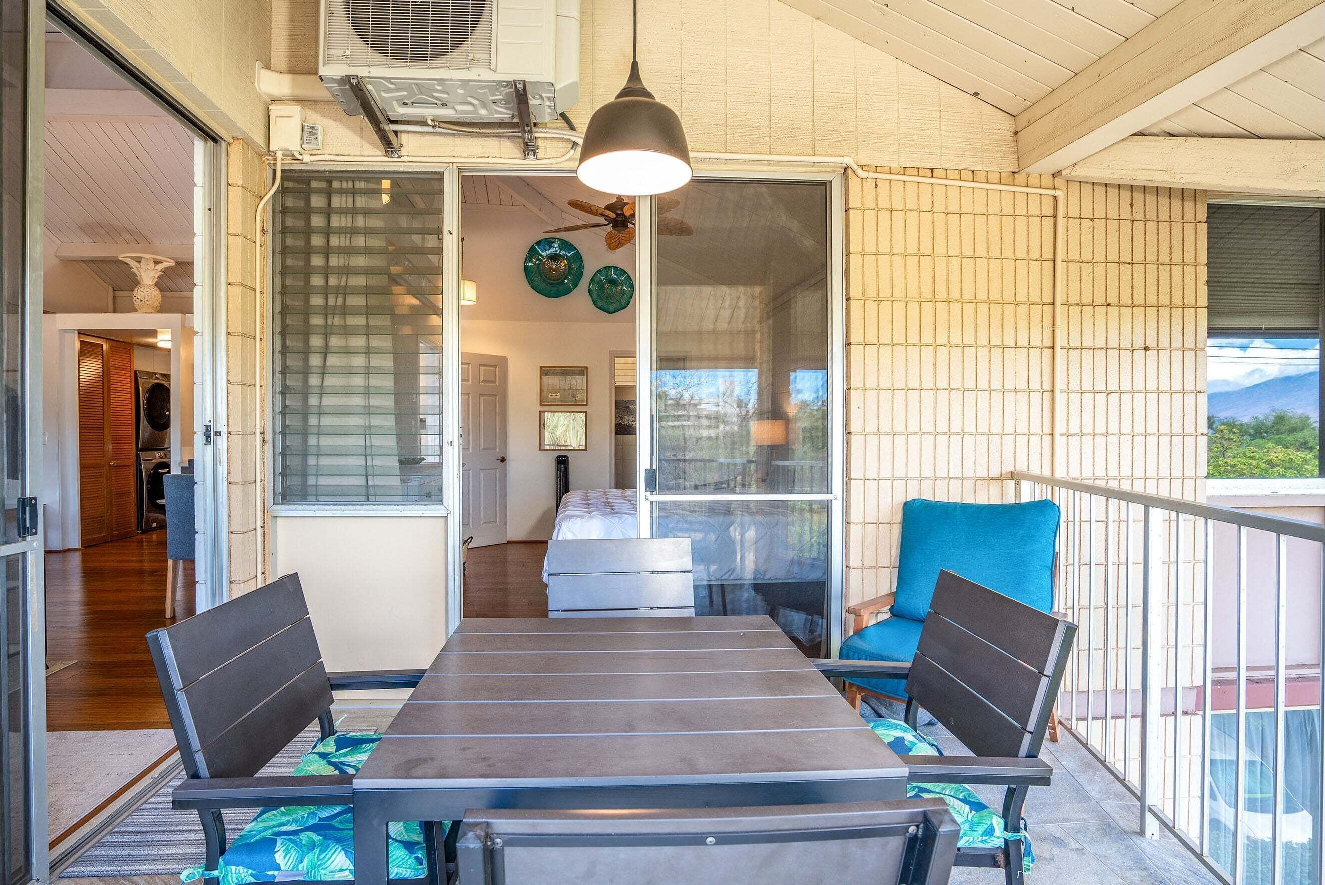Un balcón con mesa y sillas, ventilador de techo y vistas al exterior.
