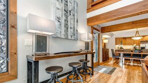 A modern kitchen with wooden beams, a dining area with a bench, and a bar with stools. - Spectacular Townhome with  a Private Hot Tub, Free WiFi, AC, & Three Fireplaces (Park City)