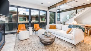 A modern living room with a sofa, chairs, a coffee table, and a staircase. - Elegant townhome with mountain view, private hot tub, fireplace & lovely decor (Park City)