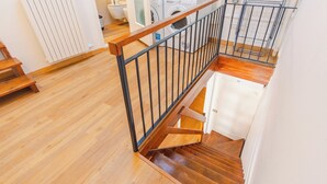 Eine Holztreppe mit Metallgeländer, die zu einem Waschraum mit Waschmaschinen führt.