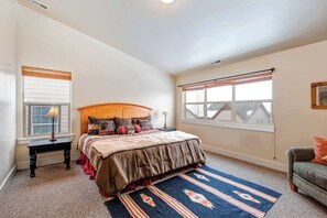 A bedroom with a bed, a nightstand, a window with blinds, a chair, and a rug. - Contemporary Home with Private Hot Tub, Fireplace, Garage Parking, & Shared Pool (Park City)