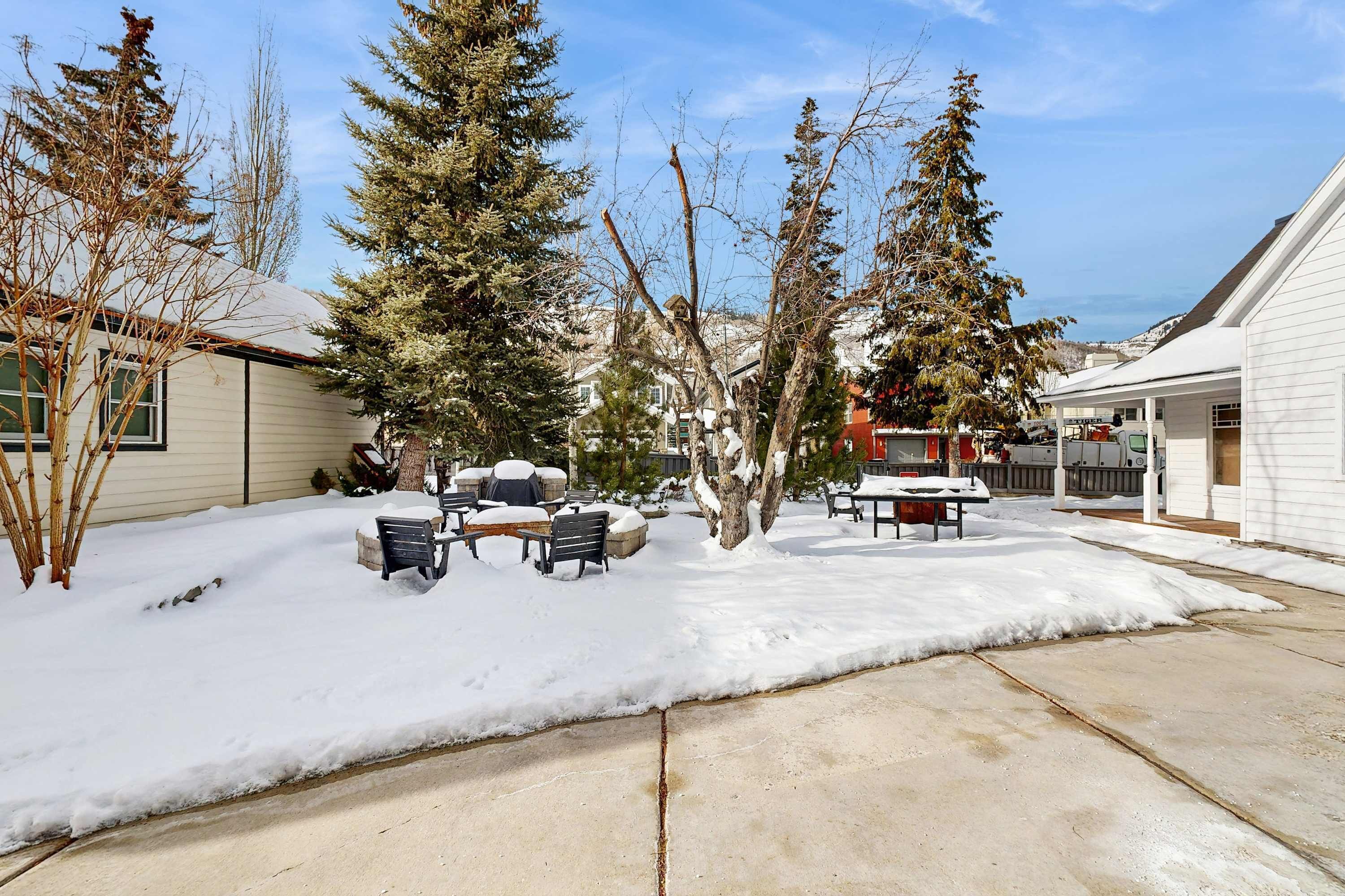 A residential area with a snow-covered yard, a patio with outdoor furniture, and a house with a visible garage.