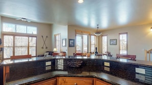Una cocina con encimera de granito curva, armarios de madera y un ventilador de techo.