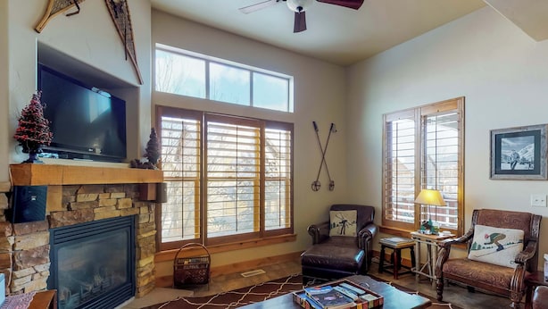 Una sala de estar con chimenea, ventanas amplias, televisor y un rincón de estar acogedor.
