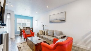 Un salon moderne comprenant un canapé, deux fauteuils, une table basse et un coin repas avec une table et des chaises.