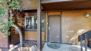 Un bâtiment en bois avec une porte portant le numéro 3, un petit porche et un arbre.