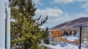 Une vue d’un bâtiment à la façade en briques, d’une voiture garée et d’un sol recouvert de neige.