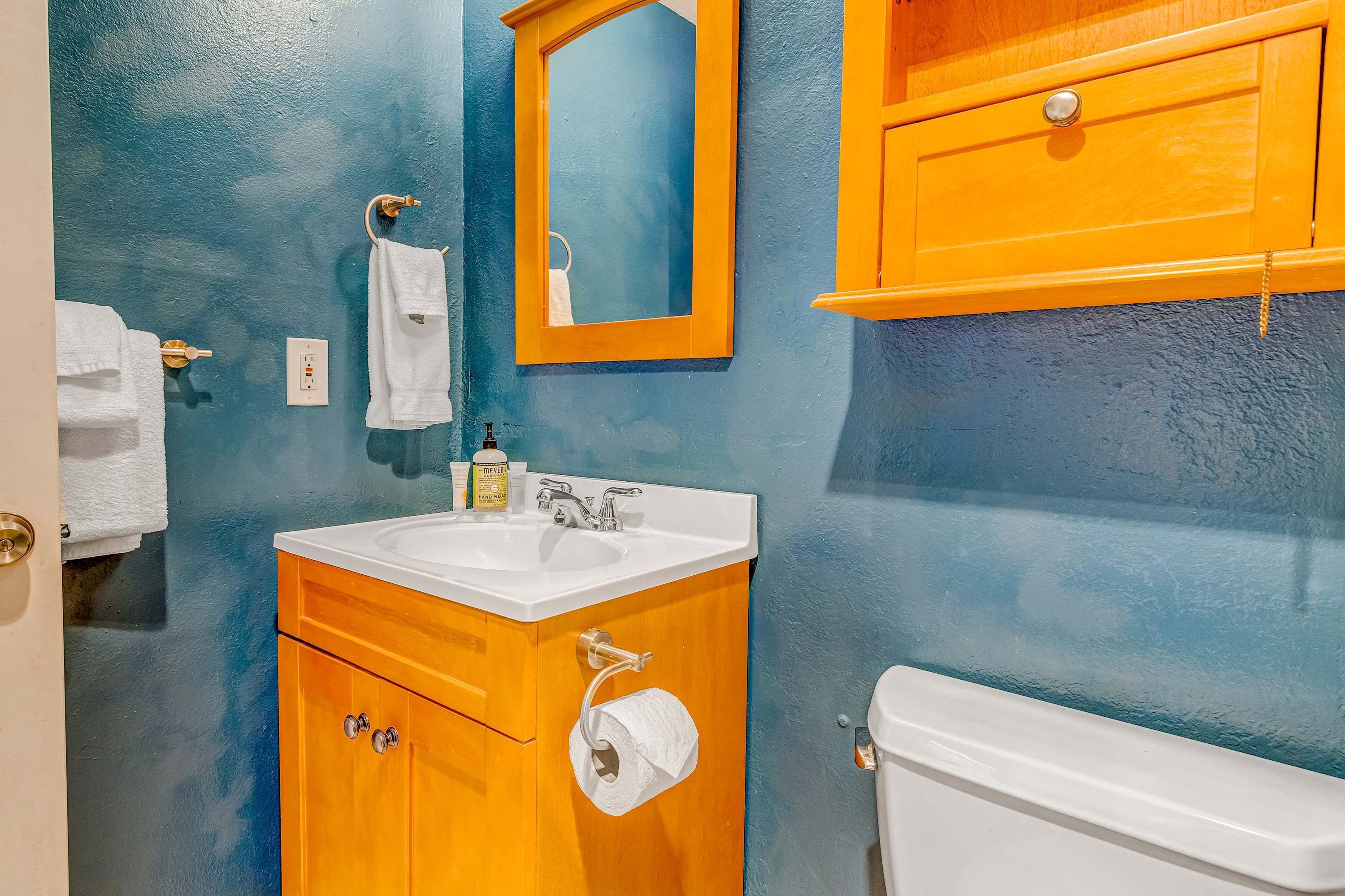 Ein Badezimmer mit Waschbecken, Spiegel, Toilette und Holzschränken.