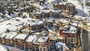 Estância nevada com vários edifícios, um teleférico de esqui e uma estrada.