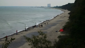 Uma praia com pessoas caminhando e uma tenda vermelha na areia.
