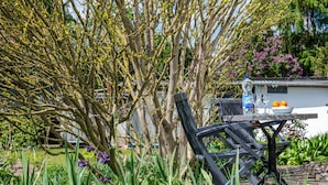 Um jardim com mesa e cadeiras, uma garrafa e uma tigela.